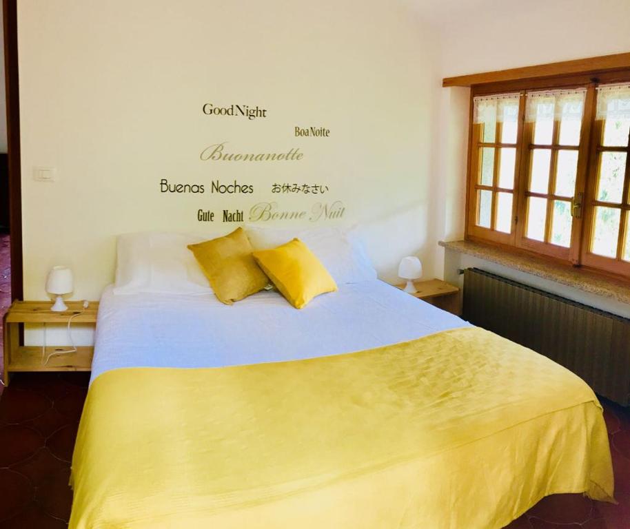 a bedroom with a bed with yellow sheets and words on the wall at Gold Cave casa vacanze relax nel bosco appartamenti in Pessinetto