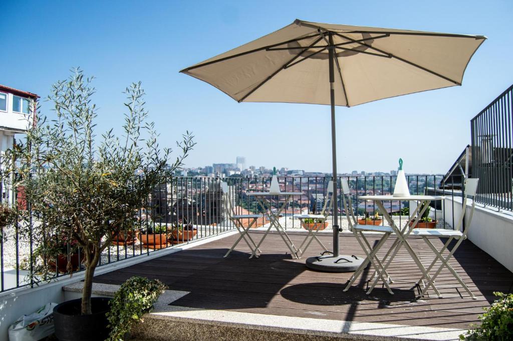 a patio with an umbrella and tables on a balcony at Douro Virtudes Apartments Historical Center in Porto