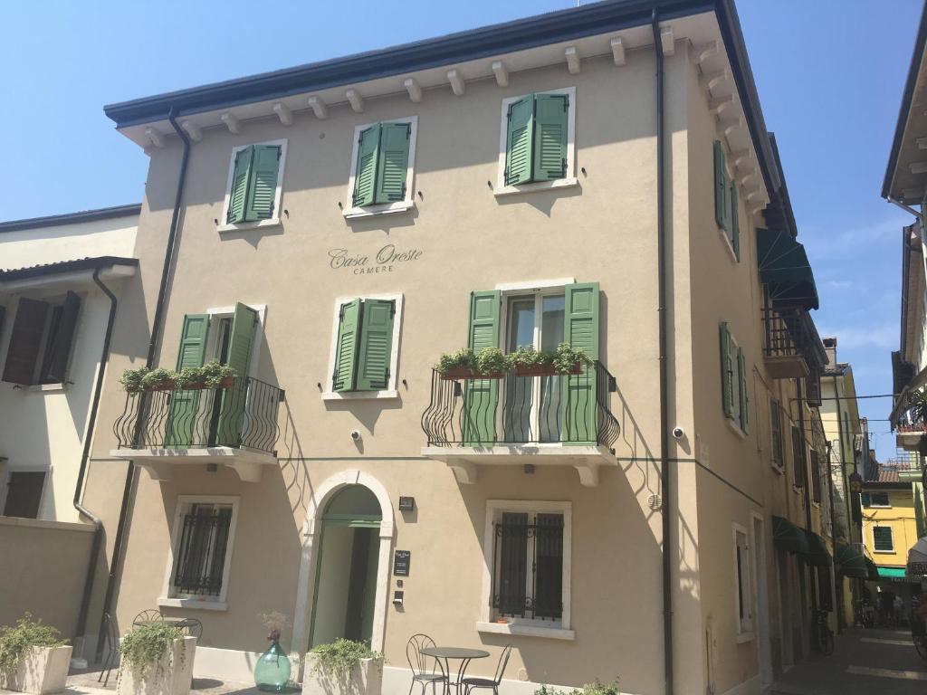 un edificio con ventanas con contraventanas verdes y patio en Casa Oreste en Lazise