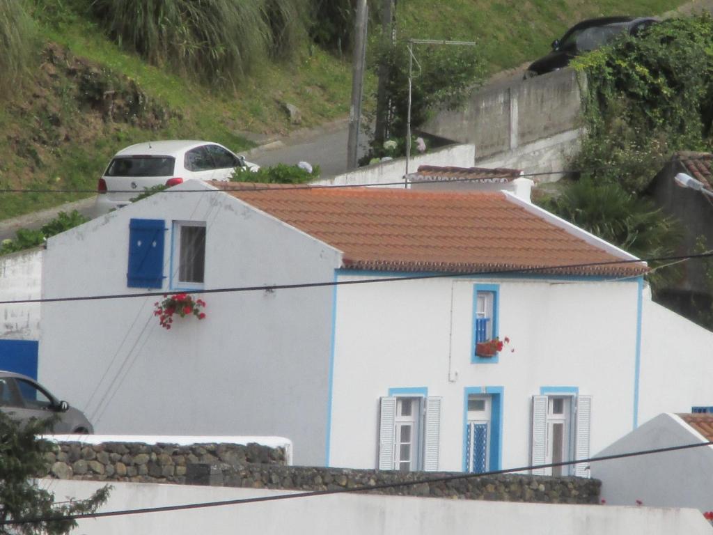 a white house with a red roof and blue windows at Ribeira da Praia House in Vila Franca do Campo