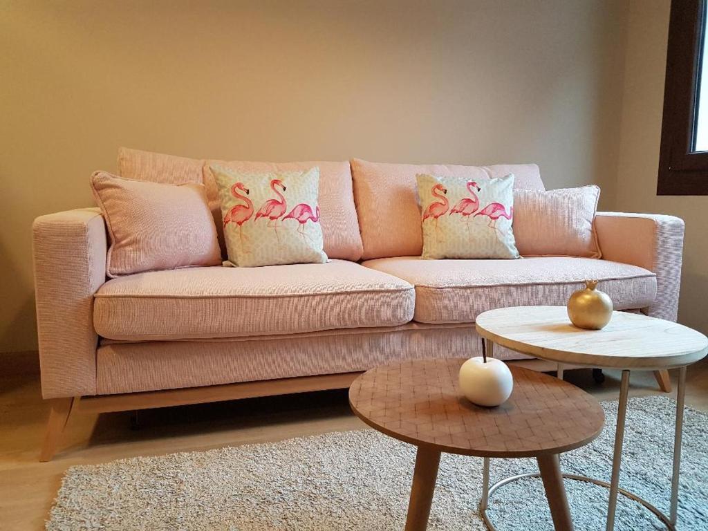 uma sala de estar com um sofá rosa e duas mesas em Apartamentos La Senda de Llanes em Llanes