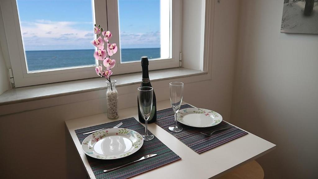 een tafel met twee borden en een fles wijn en een raam bij Boulevard de la Mer 33 Apartam 11 in Hendaye