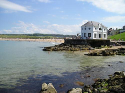 a large white house on the edge of a body of water at Albany Lodge in Portrush