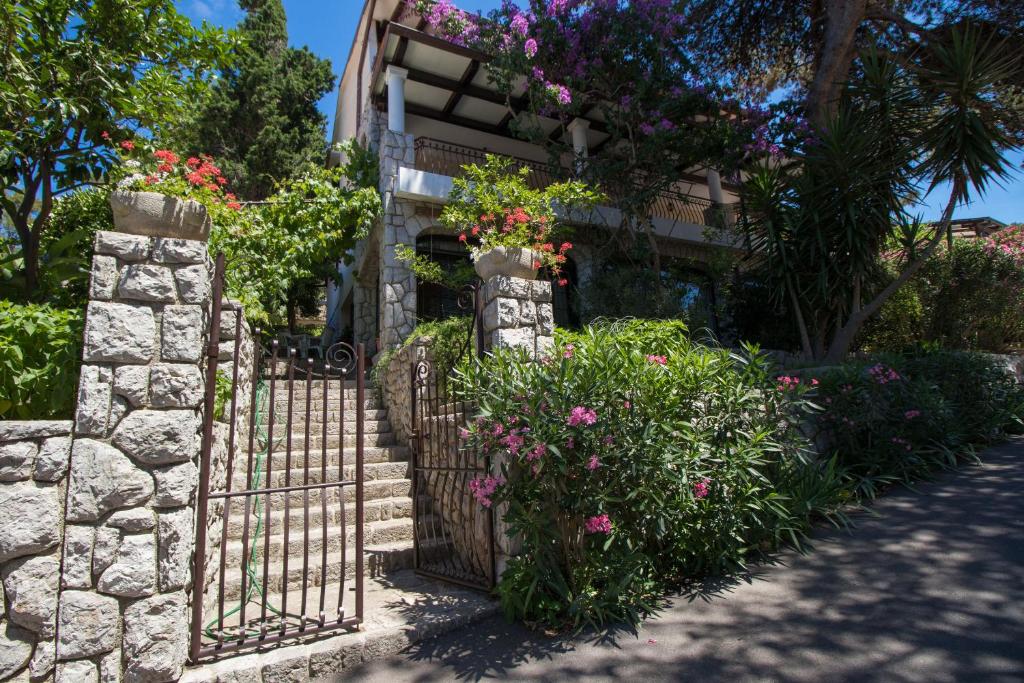a gate with flowers in front of a house at Apartments Luka in Mali Lošinj