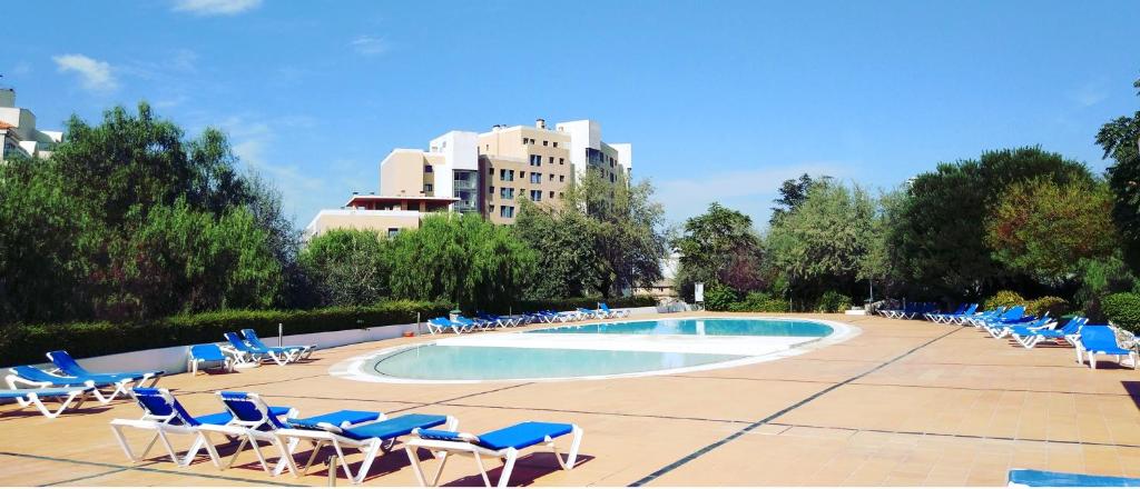 un grupo de sillas y una piscina con un edificio en Lisbon Relax Pool Apartment - Free Parking Garage, en Lisboa