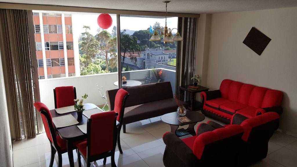 sala de estar con muebles de color rojo y ventana grande en Apartment business/airport area Guatemala City en Guatemala