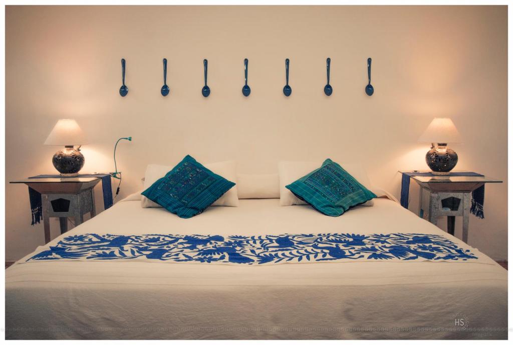a bed with blue pillows and hooks on the wall at Boca del Monte by Diablo y la Sandia B&B in Oaxaca City