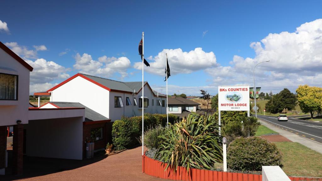 a house with two flags in front of a street at Bk's Counties Motor Lodge in Pukekohe East