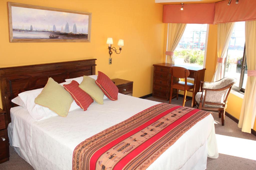 a hotel room with a bed and a desk and window at Hotel Puerto Mayor in San Antonio