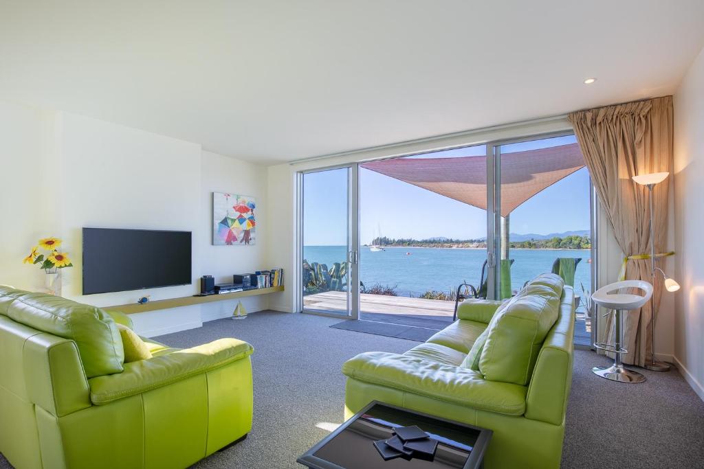 Sala de estar con 2 sillas verdes y TV en Mapua Wharfside Apartments en Mapua