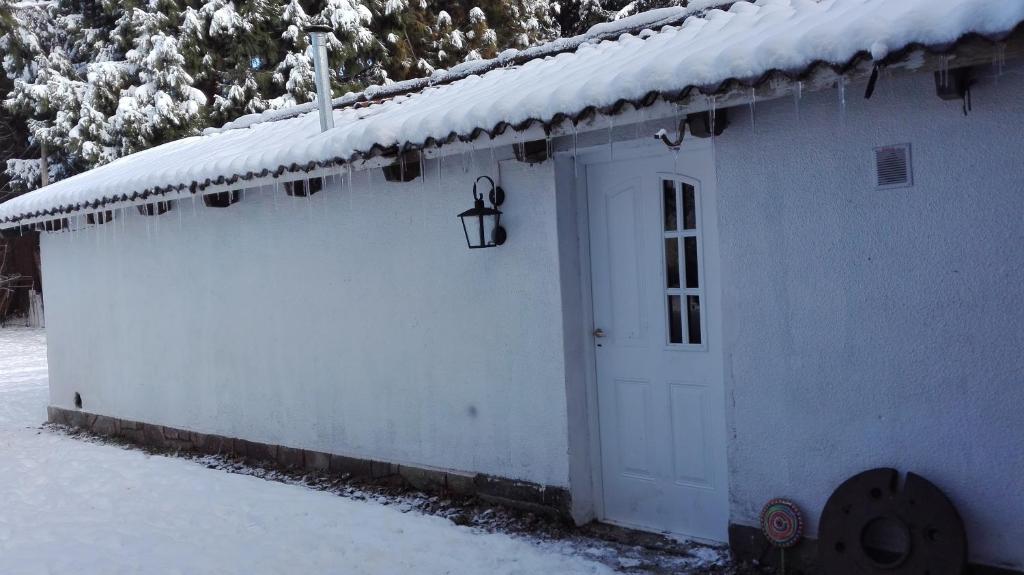 a white building with a door in the snow at Donde brilla el sol in Dina Huapi