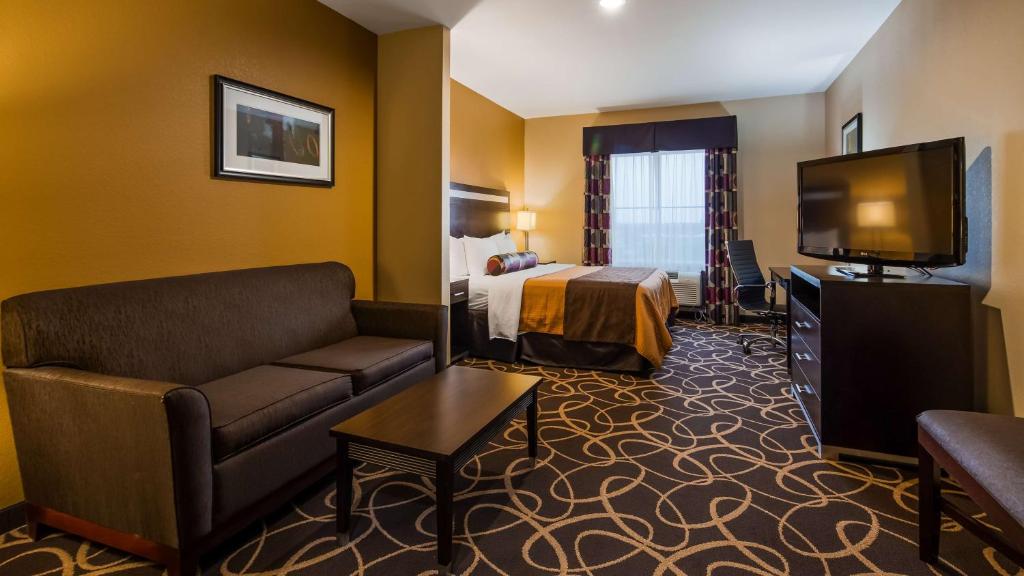 a hotel room with a bed and a couch and a television at Best Western Plus Kenedy Inn in Kenedy