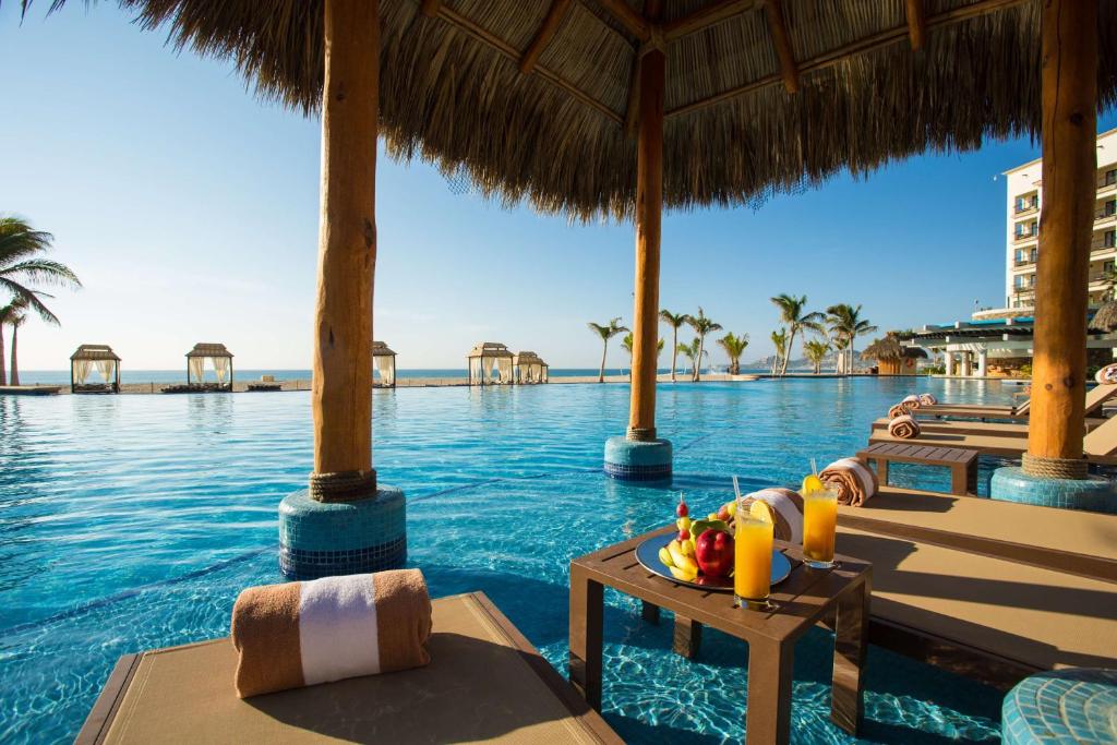 a resort pool with a table with fruit on it at Hyatt Ziva Los Cabos - All Inclusive in San José del Cabo