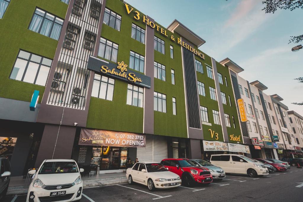 een groep auto's geparkeerd voor een gebouw bij V3 Hotel & Residence Seri Alam in Pasir Gudang