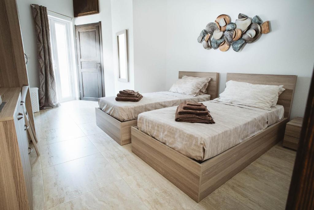 two beds in a room with white walls at Fauzia B&B in Hamrun