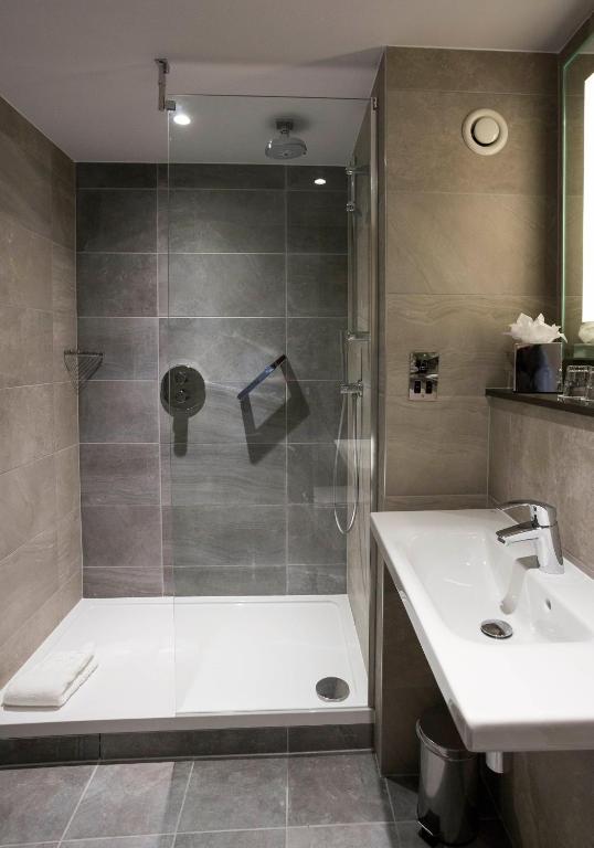 a bathroom with a shower with a tub and a sink at Maldron Hotel Kevin Street, Dublin City in Dublin