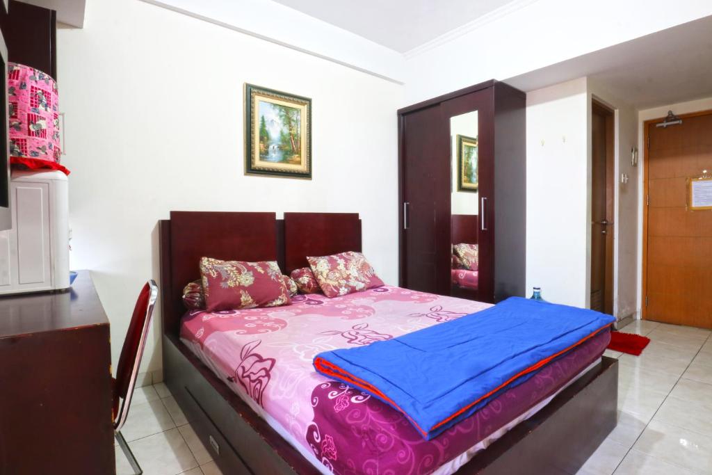 a bedroom with a bed with pink and blue sheets at Dewi Depok Apartment Margonda Residence 2 in Depok