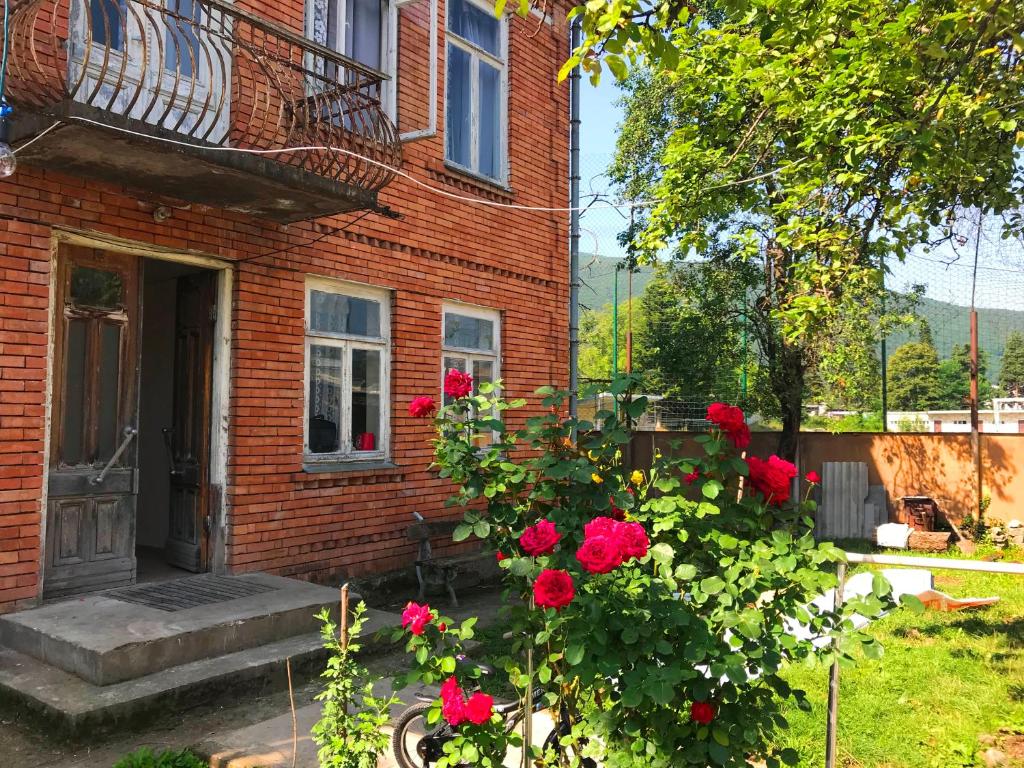 a brick house with red roses in front of it at AMBROsador in Ambrolauri