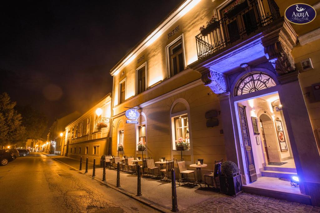 a building with tables and chairs on a street at night at Arbia Dorka Heritage Palace in Varaždin