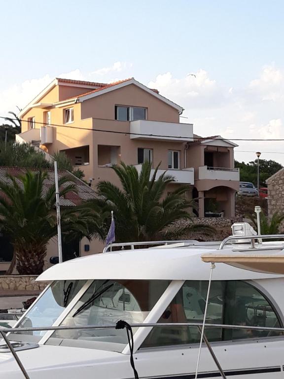 a white boat parked in front of a house at Apartmani Goga - Molat 6 in Molat