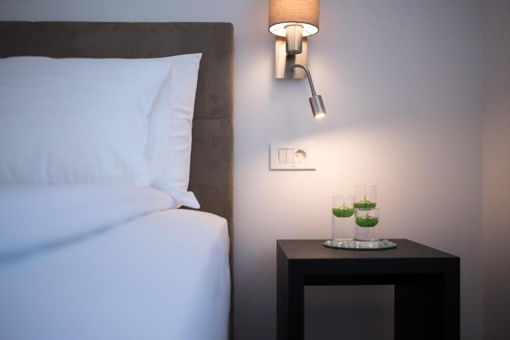 a bed and a table with two glasses on it at Pansion Leggero in Krk