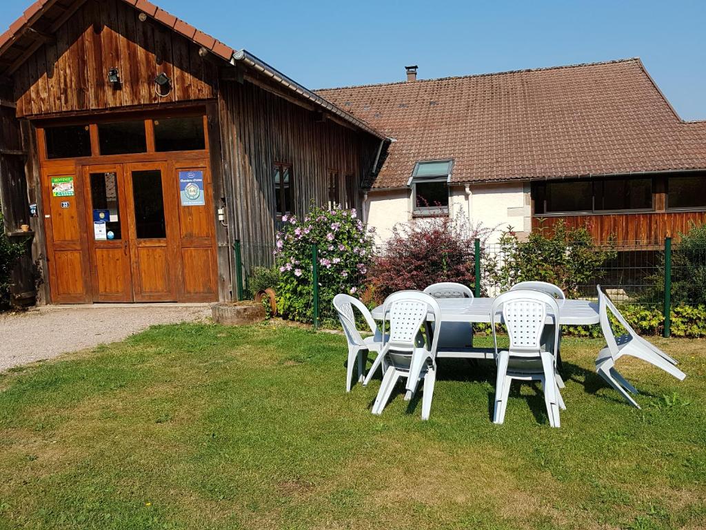 une table et des chaises sur l'herbe devant un bâtiment dans l'établissement Gite le Sauceley Maison de vacances pour 6 à 10 personnes, à Girmont-Val-d'Ajol