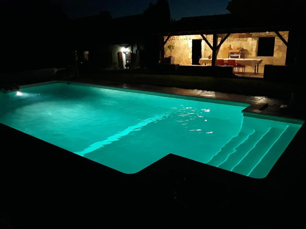 ein nachts beleuchteter Pool in der Unterkunft La Girafe Bleue in Lunas