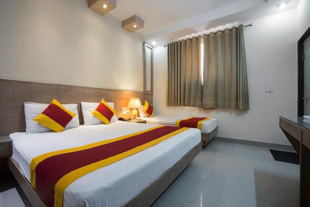 a hotel room with two beds and a window at Hotel Baba Inn-By RCG Hotels in New Delhi