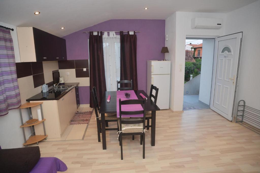 ビオグラード・ナ・モルにあるApartments Barićの紫の壁のキッチン(テーブル、椅子付)