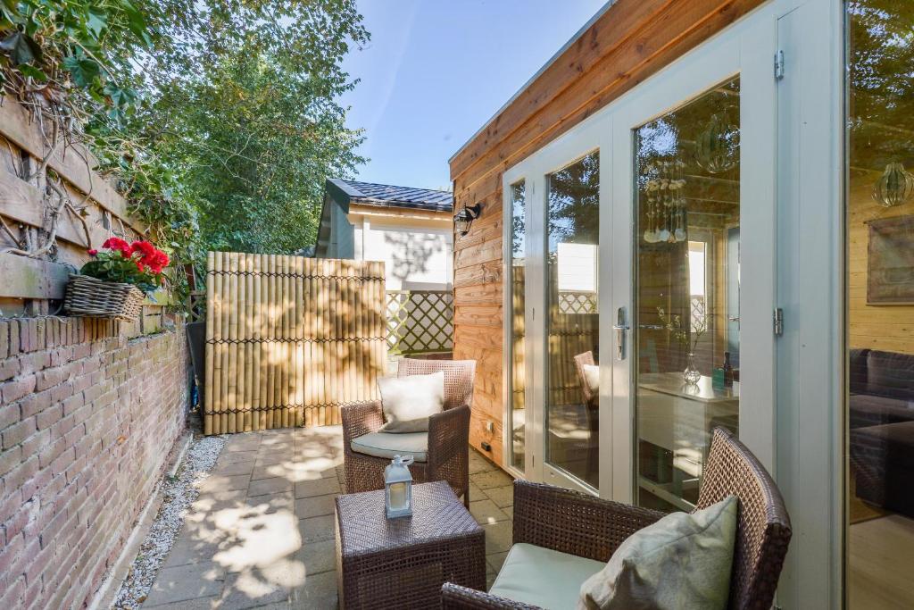 Un patio con sillas de mimbre y una mesa. en Moyo Kijani, en Zandvoort