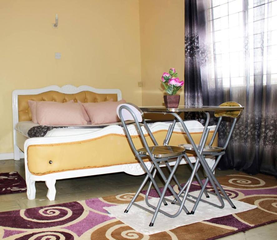 Kenya Inn في نيروبي: غرفة نوم بسرير وطاولة وكراسي
