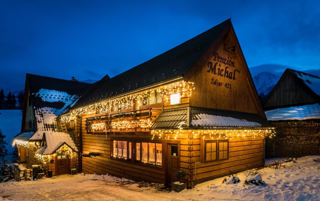 um edifício coberto de luzes de Natal na neve em Penzión Michal em Ždiar