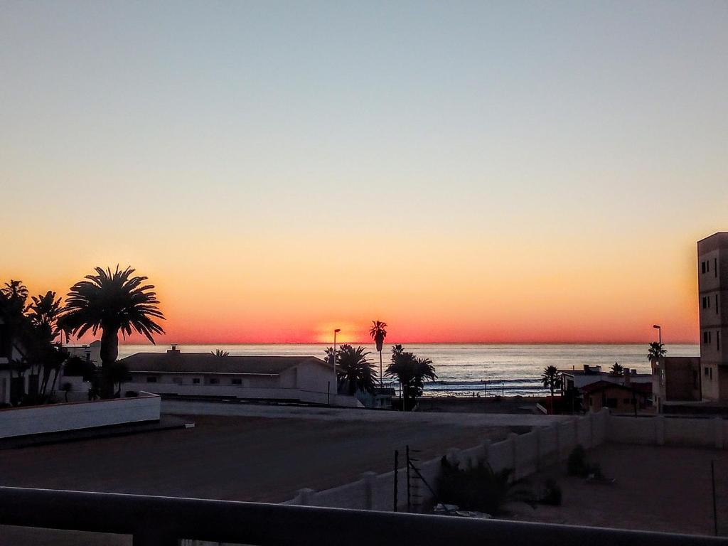 um pôr-do-sol sobre uma praia com palmeiras e o oceano em Sea View Bliss Guesthouse with self Catering em Swakopmund