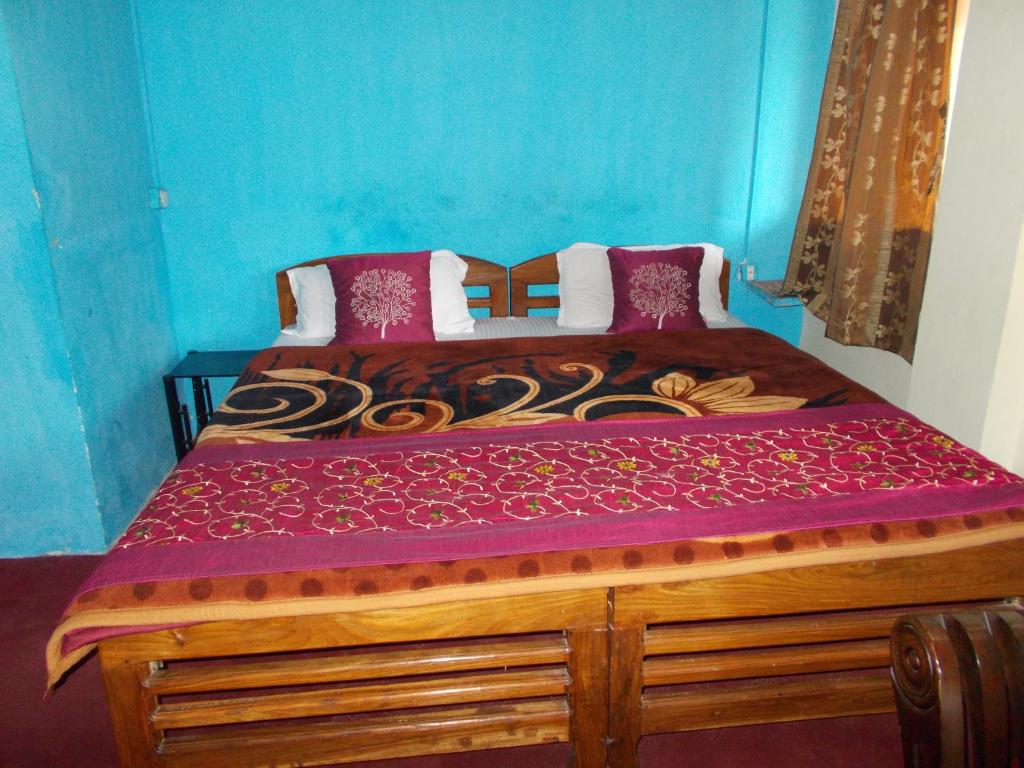 a bedroom with a wooden bed with a purple comforter at Hotel Raj Mahal(100 metres from Mall road) in Nainital