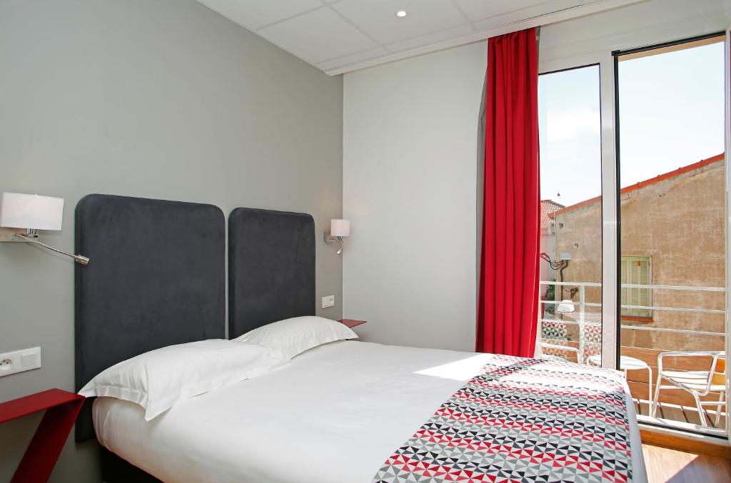 a bedroom with a bed and a large window at Hôtel Méditerranée in Calvi