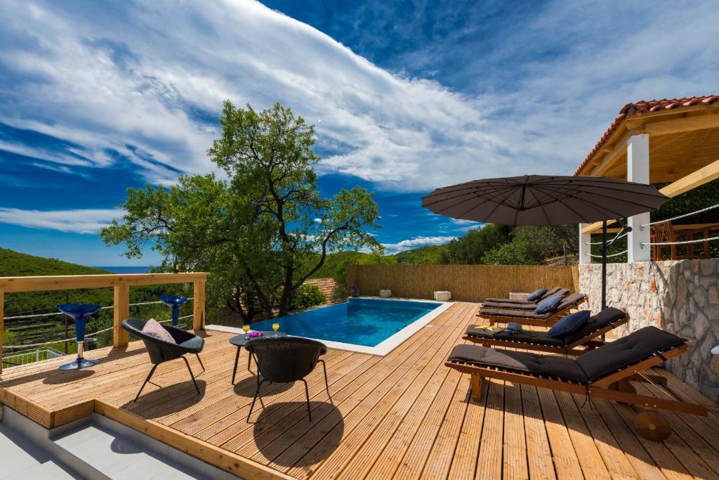 eine Terrasse mit Stühlen, einem Sonnenschirm und einem Pool in der Unterkunft Villa Dundo Pero in Babino Polje