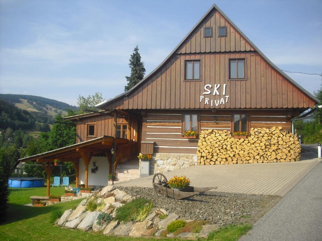 een groot houten huis met een stapel brandhout bij Privat SKI Erlebach in Rokytnice nad Jizerou