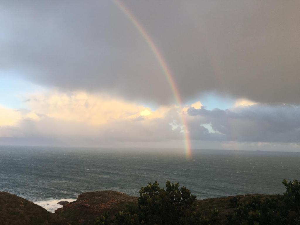een regenboog in de lucht boven de oceaan bij Tranquillo in Mosselbaai