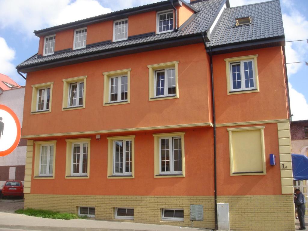 uma casa laranja com um telhado preto em Pokoje Gościnne na Podzamczu em Darłowo