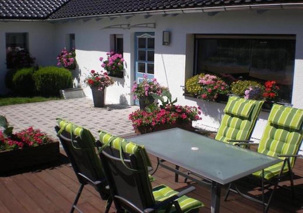 a table and chairs on a patio with flowers at Ferienhaus Nadine 2023 komplett saniert in Bad Brambach