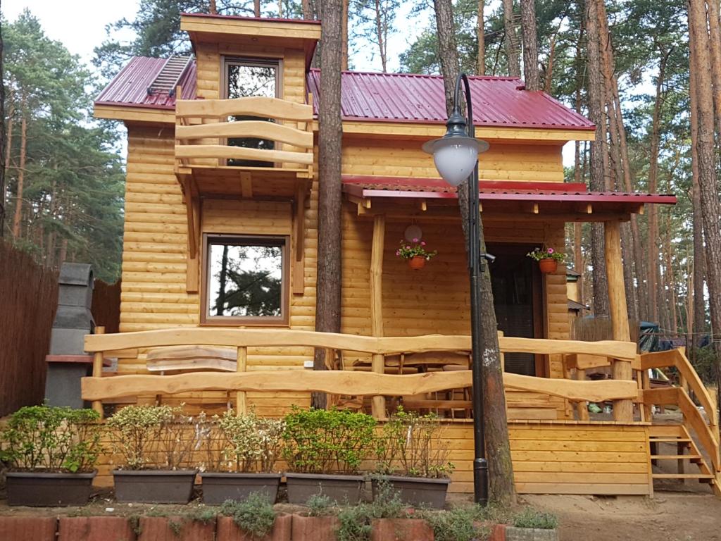 a log cabin in the woods with a red roof at Domek Fiona in Boszkowo
