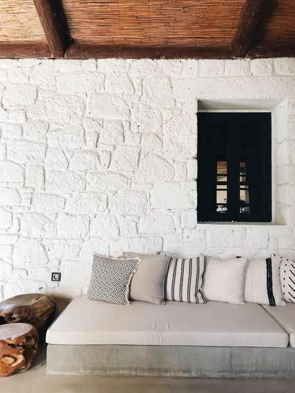 a couch against a white brick wall with a window at GAIA ALAÇATI in Alaçatı