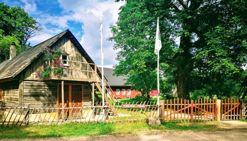 an old wooden house with a fence and a flag at Värava Farm in Pidula