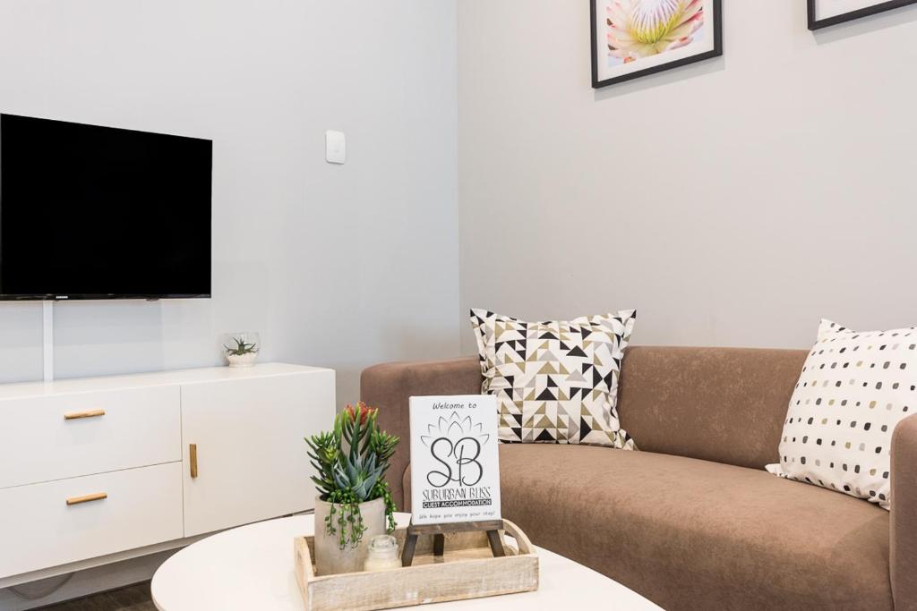 ein Wohnzimmer mit einem Sofa und einem TV in der Unterkunft Suburban Bliss Durbanville in Kraaifontein