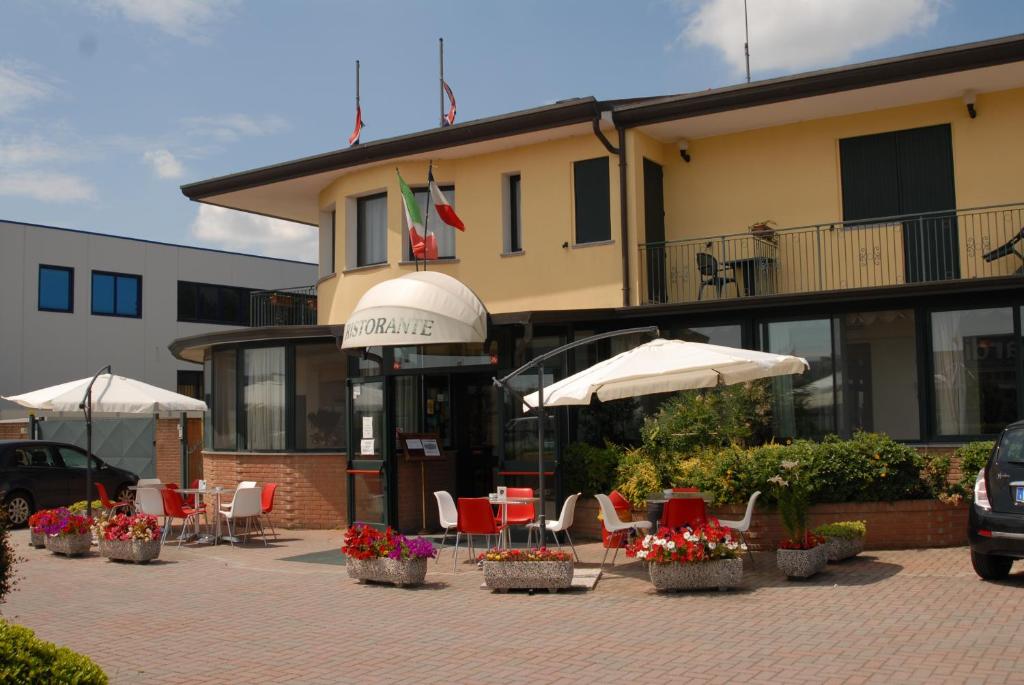 a patio with chairs and umbrellas in front of a building at Hotel Gran Delta in Rosolina