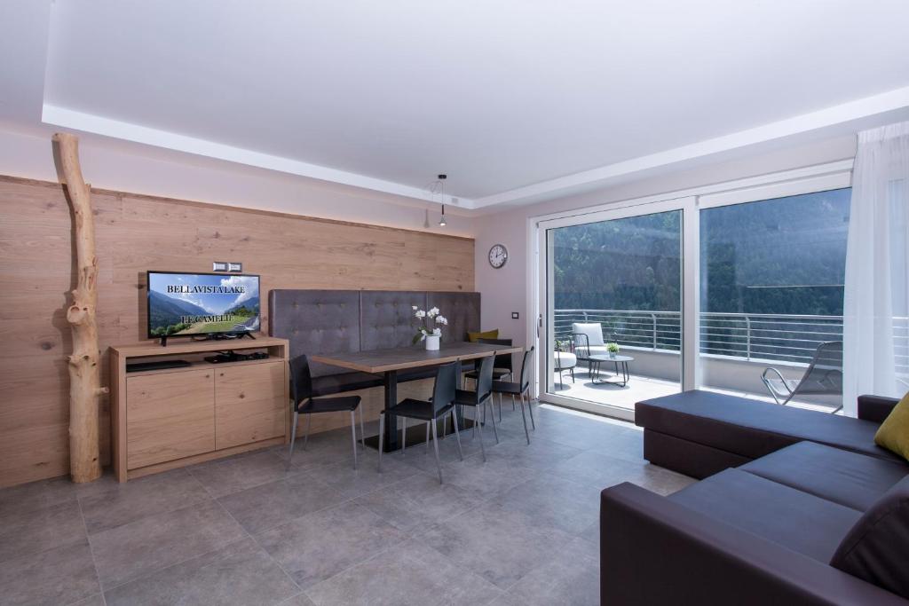 uma sala de estar com um sofá e uma mesa com uma televisão em Bellavista - Lake em Molveno
