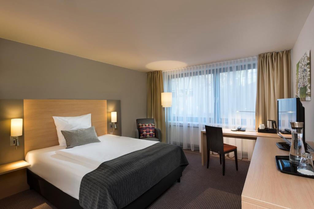 Habitación de hotel con cama y escritorio en Mercure Hotel Düsseldorf Neuss en Neuss