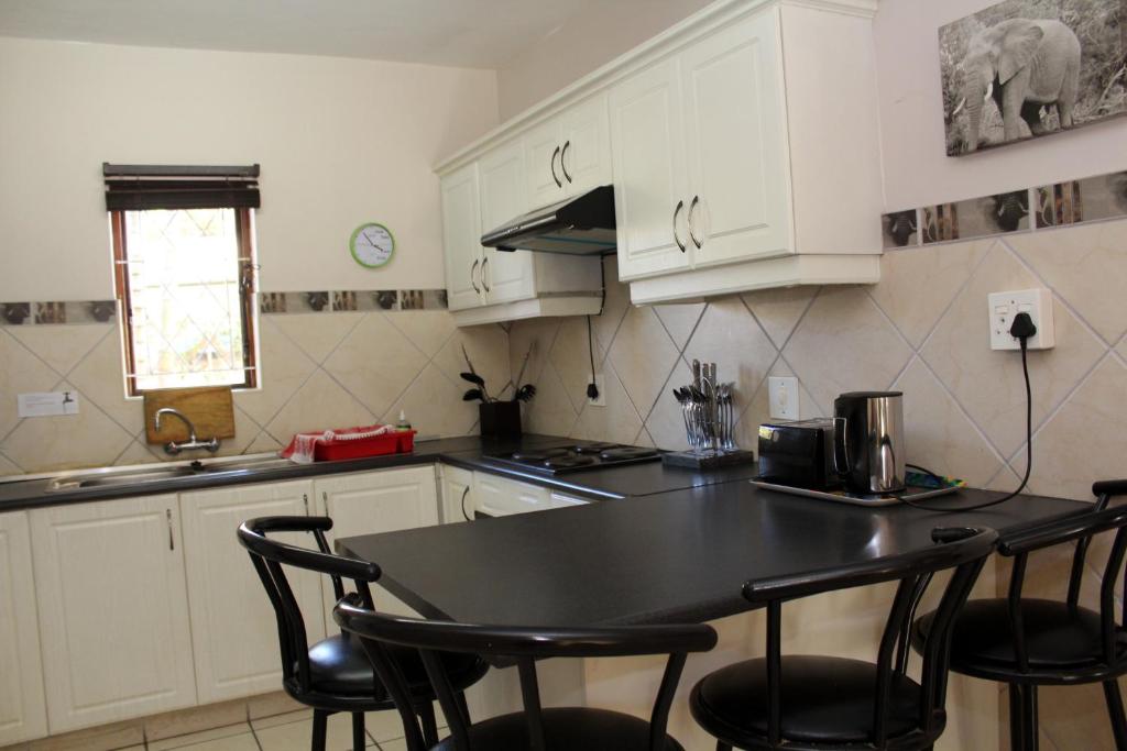 a kitchen with white cabinets and a black table and chairs at 9 The Bridge Holiday Resort in St Lucia