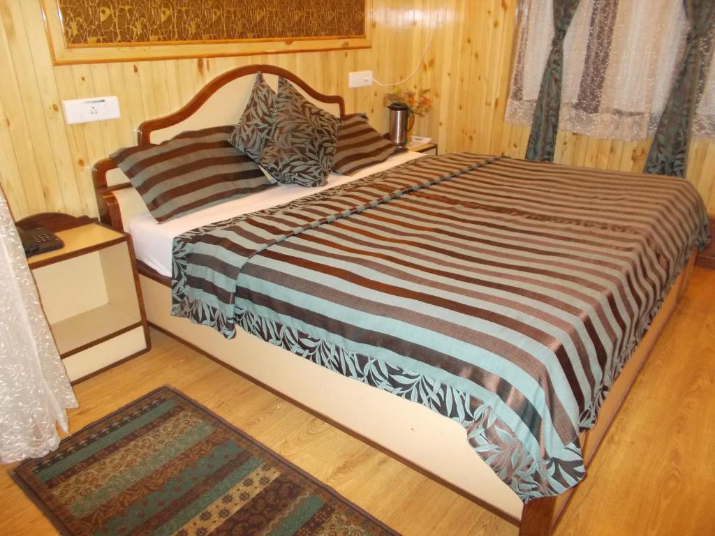 een slaapkamer met een groot bed en een gestreepte deken bij Comfortable Rooms Fitted With Modern Amenities in Nainital