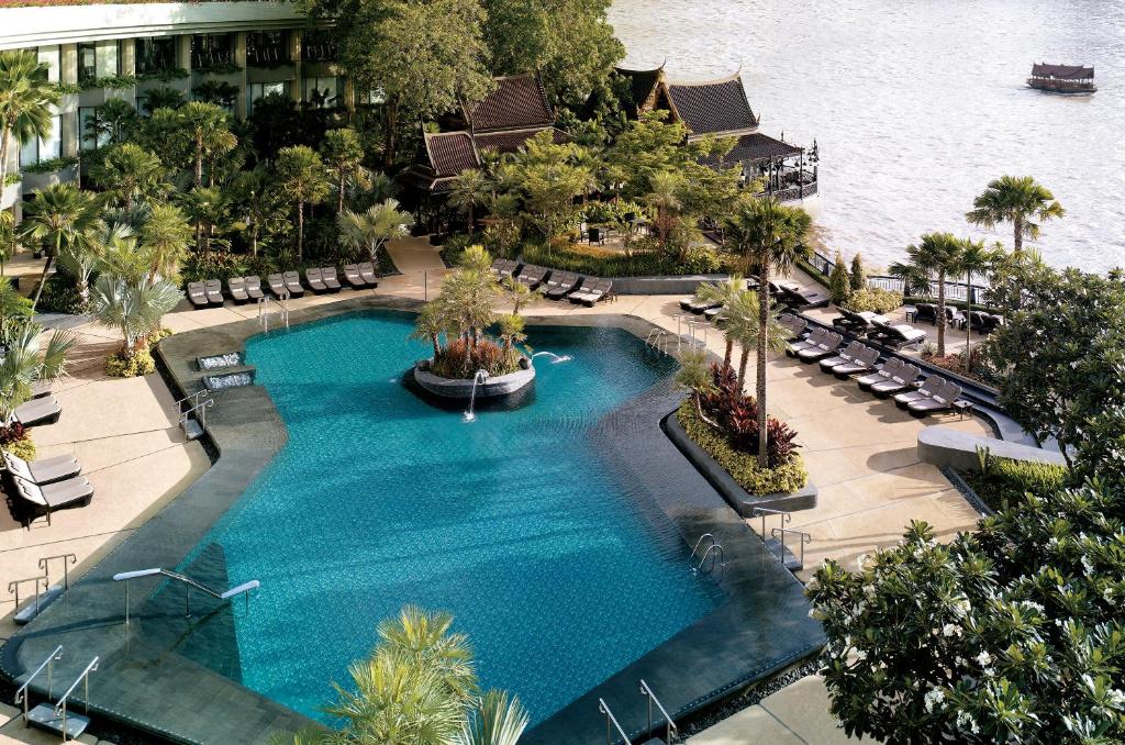 An elevated view of a landscaped riverside pool surrounded by loungers and tropical planting.